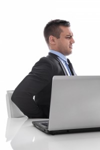 8347921-pain-businessman-sitting-with-backache-at-desk-isolated-on-white-background